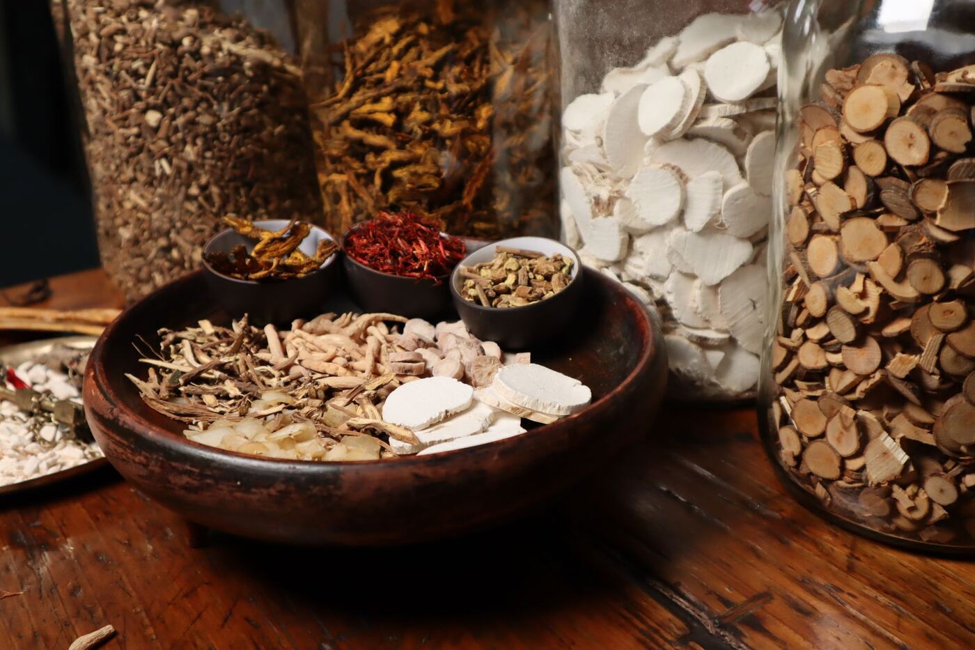 Traditional Chinese herbal medicines in wooden bowls and glass jars used for custom formulas