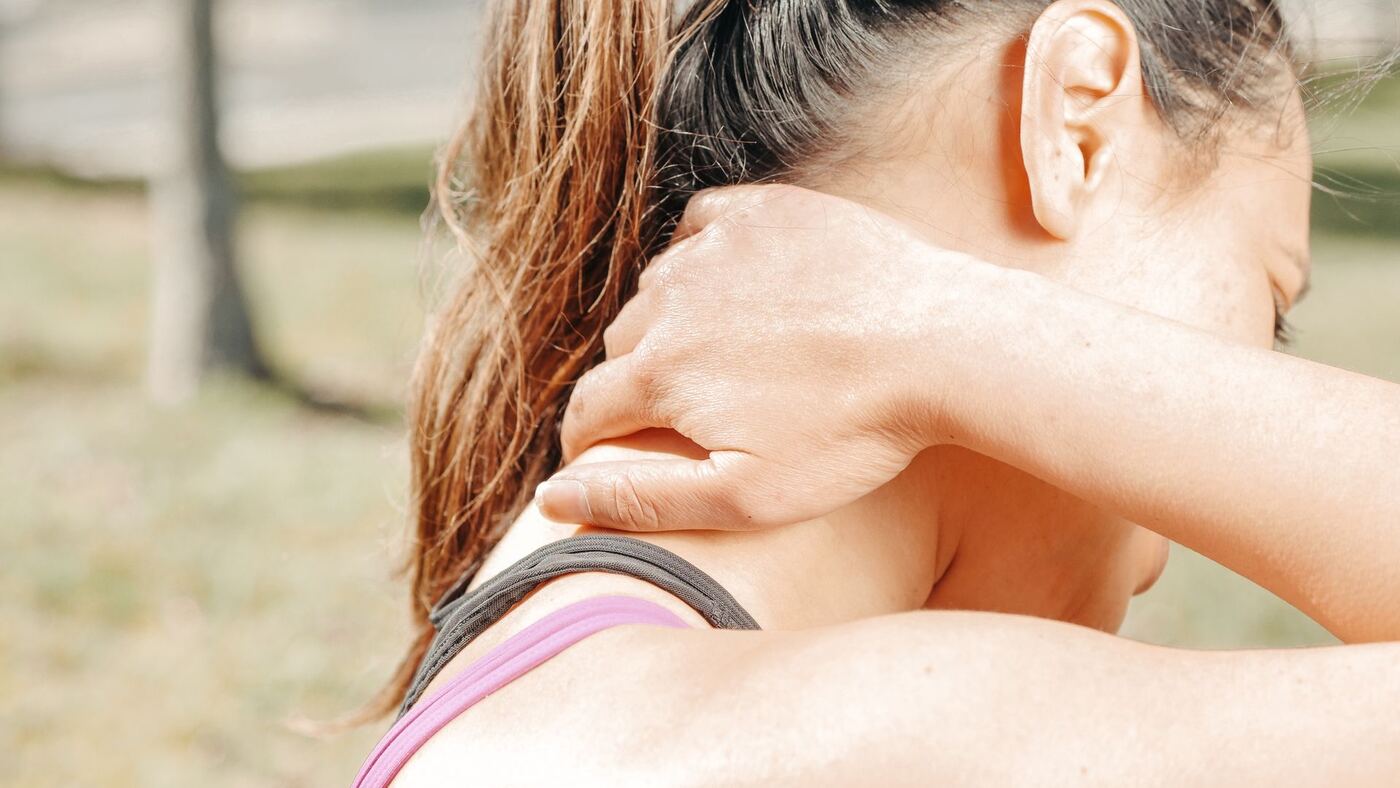 Woman holding her neck from chronic neck pain treated with acupuncture in Morristown
