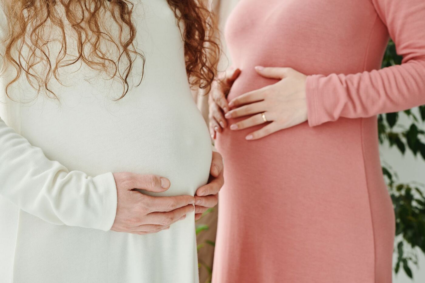 Two expecting mothers holding their bellies, representing women's health care